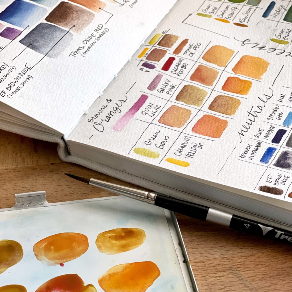 An open sketchbook showing orange and brown color mixes.