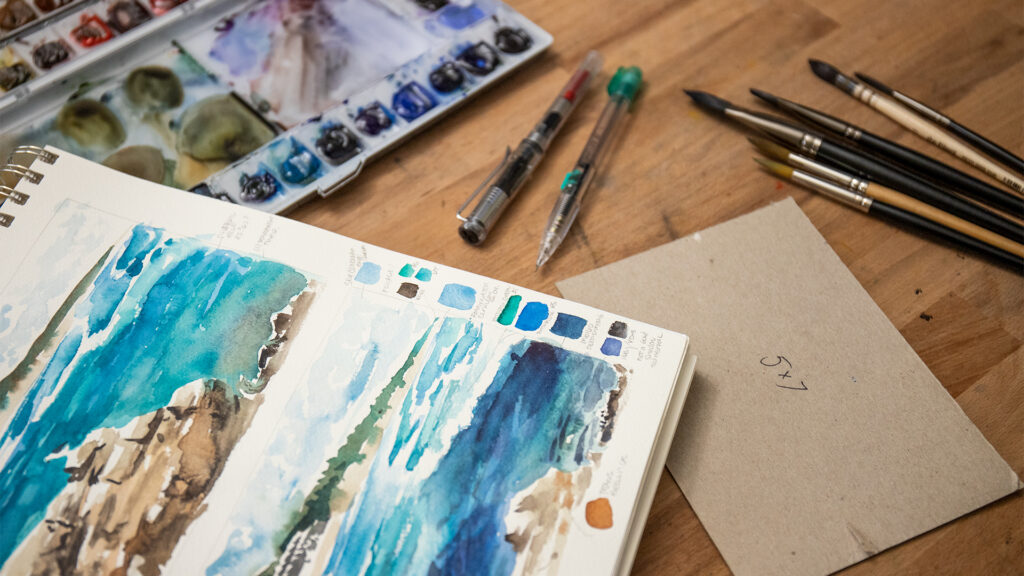 Thumbnail including a sketchbook that has a watercolor sketch with swatches in the margins.